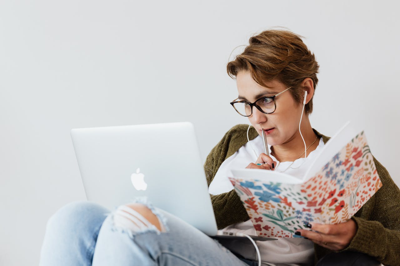 Concentrated woman using laptop and taking notes